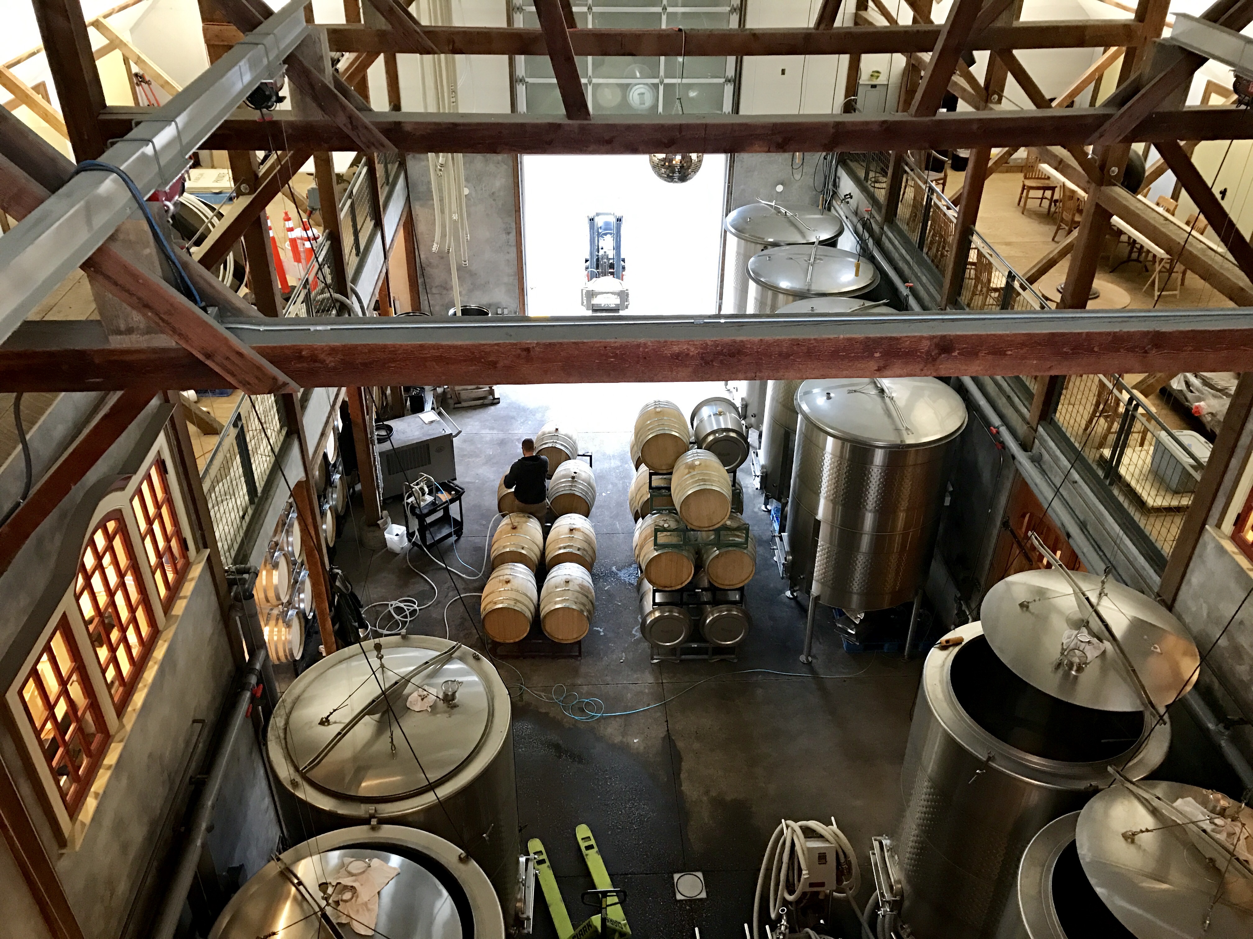 Working winery production floor with barrels and fermentation tanks